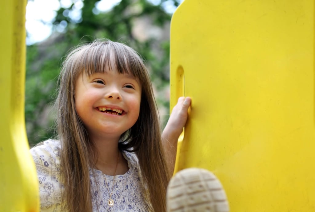 bambina sorridente sullo scivolo, con sindrome di down