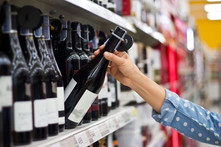 scelta di una bottiglia di vino dagli scaffali di un supermarket, vino e etichettatura degli alcolici