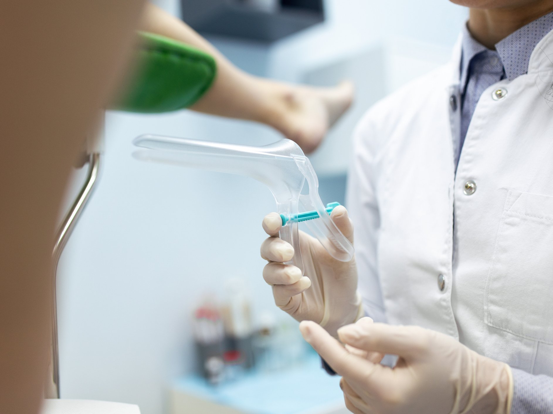 Professionista sanitario prepara uno speculum per esame ginecologico, in contesto di screening cervicale con Pap test.