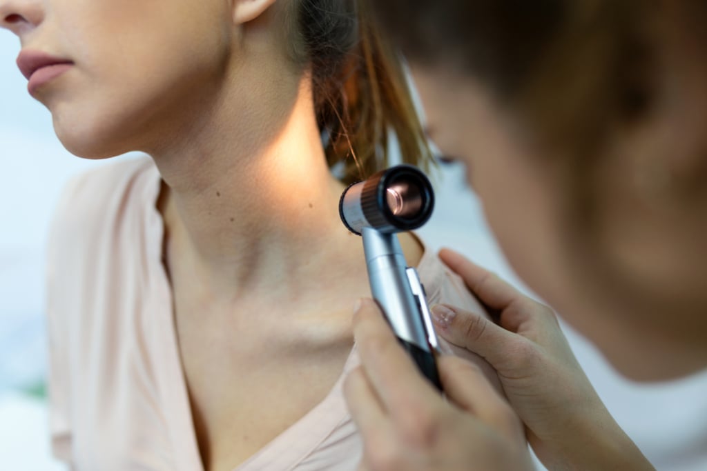 Medico esamina con l'epiluminescenza i nei di una paziente per cercare eventuali melanomi