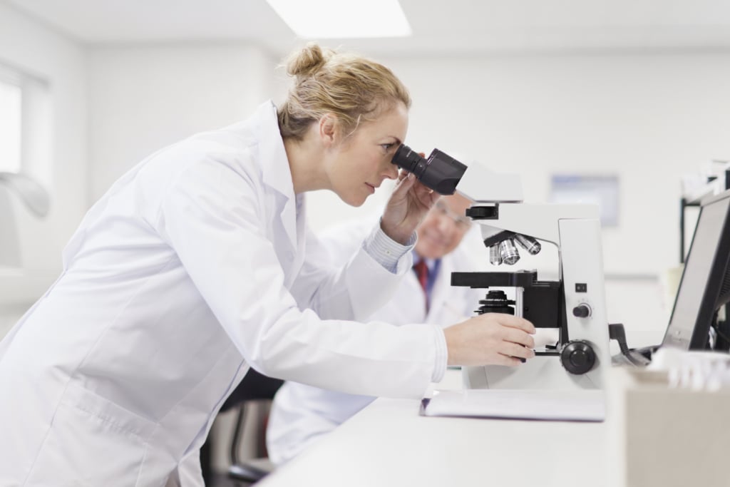 Ricercatrice osserva al microscopio cellule tumorali
