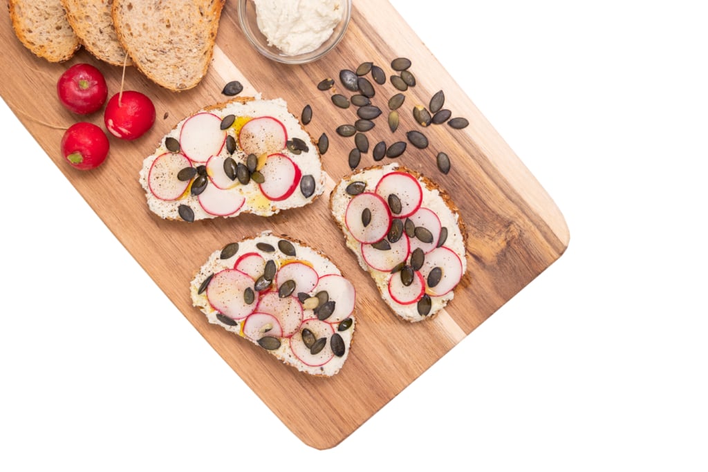 Crostini conditi con una crema di tofu e mela, guarniti con ravanelli e semi di zucca